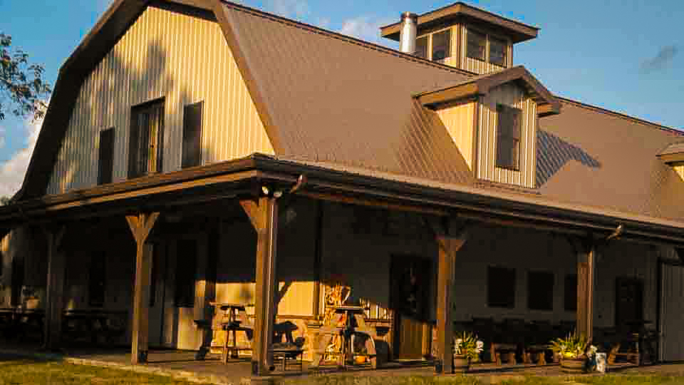 brown barndominium with porch and picnic tables